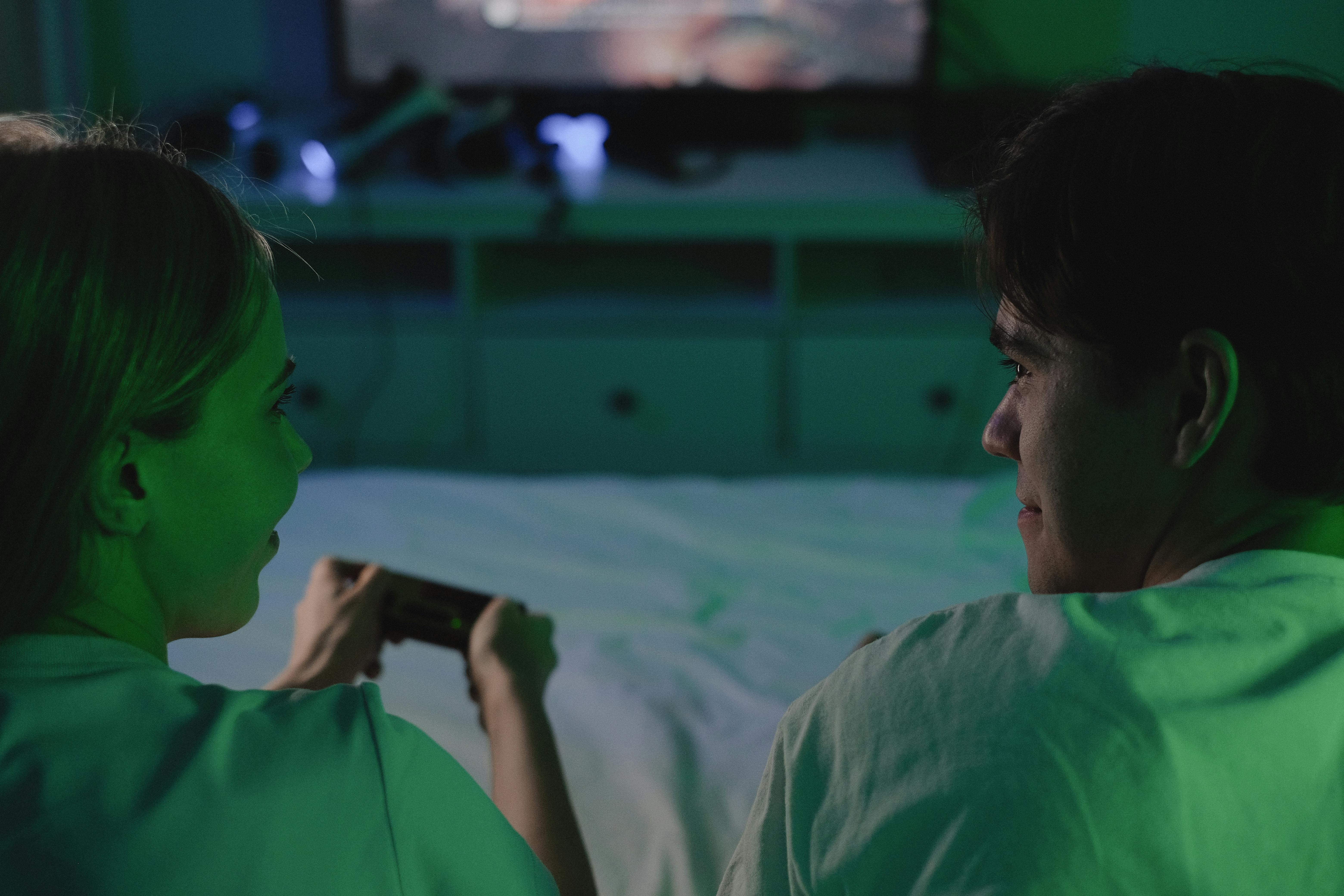 A couple enjoying a video game together in a dimly lit bedroom setting.